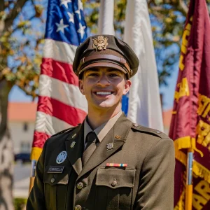 Brian Femminella in a formal military uniform smiling outdoors, standing in front of several flags