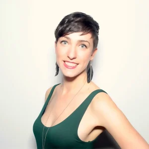 Luna Ray smiling brightly in a sleeveless green top against a plain light background.