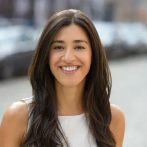 Smiling Marisa Hodgdon with long dark hair standing outdoors in soft natural light.